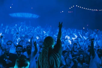 Image of DJ doing gun-fingers hand gesture to dancing crowd at Outlook Origins Festival
