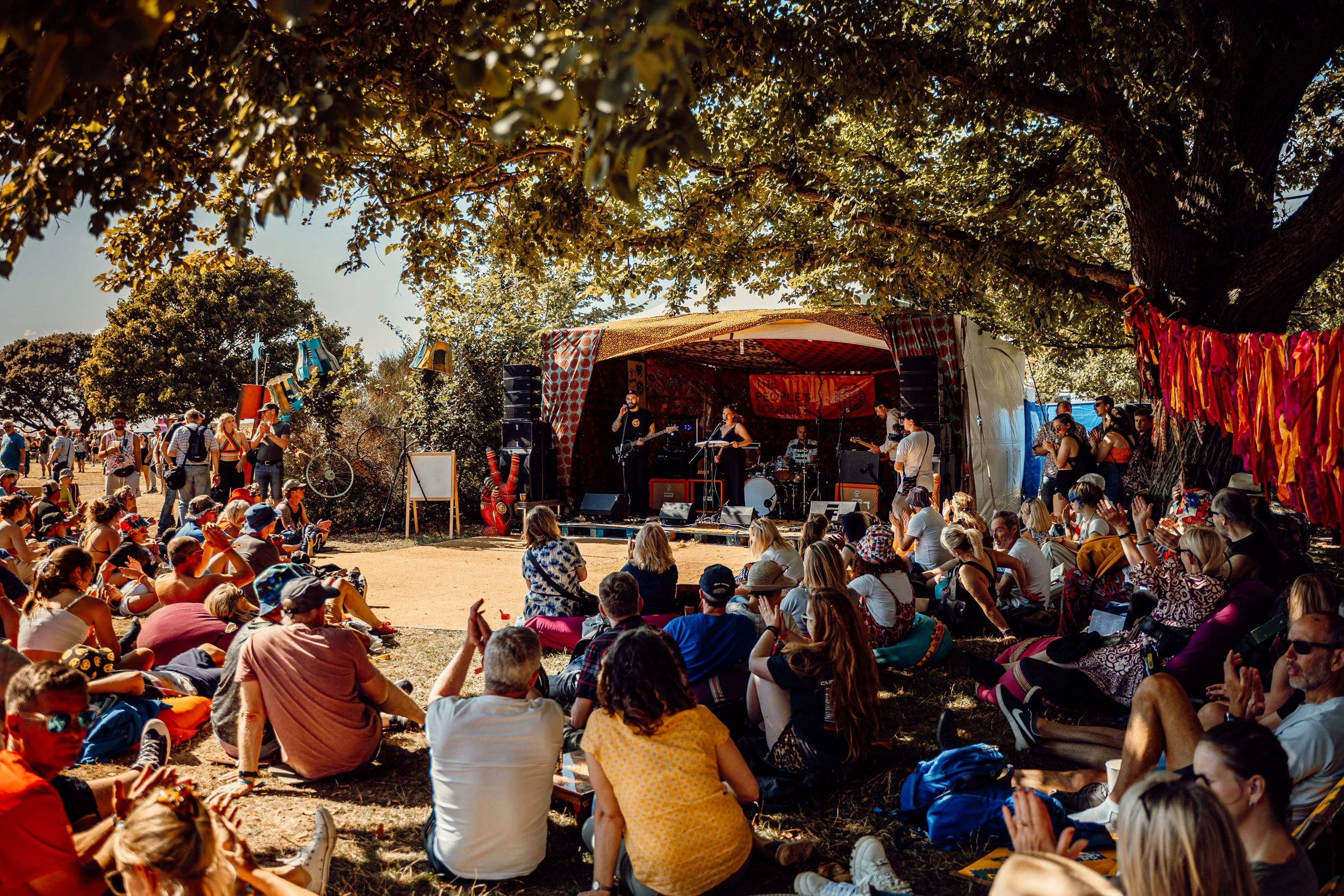 Image of band playing intimate set to a crowd who are sat down relaxing while listening
