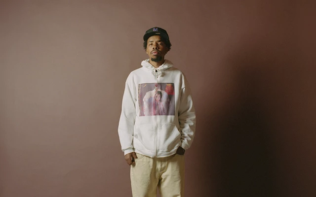 Earl Sweatshirt standing in front a brown backdrop